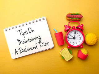 food and alarm clock with the words tips on maintaining a balanced diet.