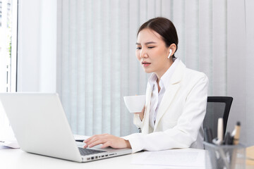 Businesswoman's hand presses on a laptop keyboard and holding a cup of hot coffee, Sitting in a private office, Using computers to conduct financial transactions, World of technology and internet...