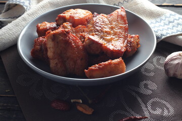 Fried Pork Belly with Fish Sauce Served on a Gray plate on a black wooden floor.
