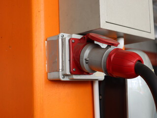Industrial electric cable sockets are mounted on orange concrete poles.
