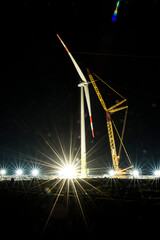 Landscape with construction site of wind turbine towers by big crane at night. Industrial concept...