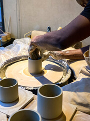 A man throwing a clay mug on a potters wheel
