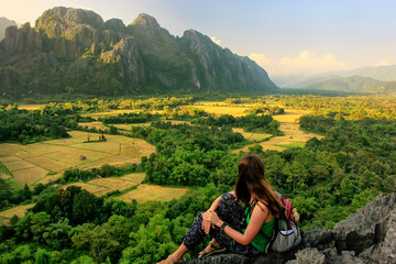 Fototapeta na wymiar Young woman enjoying the view of farm fields in Vang Vieng, Laos