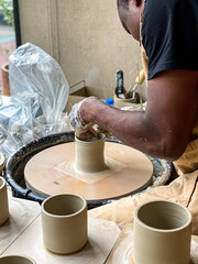 A man throwing a clay mug on a potters wheel