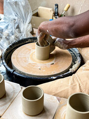 A man throwing a clay mug on a potters wheel