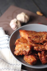 Fried Pork Belly with Fish Sauce Served on a Gray plate on a black wooden floor.