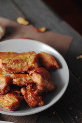 Fried Pork Belly with Fish Sauce Served on a Gray plate on a black wooden floor.
