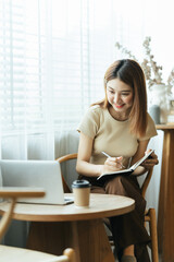 Portrait of Asian young female working on laptop and financial report at office.