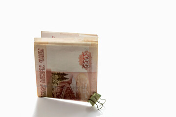 Money with a face value of five thousand rubles is folded in half and fastened with a stationery clip.