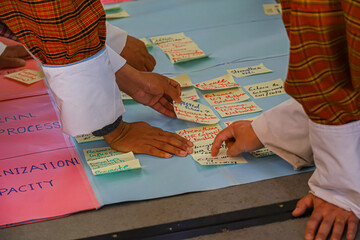 Hands arranging sticky notes with balanced scorecards strategic plans