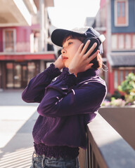 Happy young asian woman listening to music with headphones on the street.