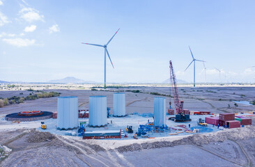 Mobile crane and wind turbine under the blue sky. Wind power plant under construction with several foundations constructed to reduce global warming and climate change