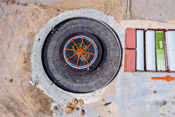 Aerial view at the construction site of the foundations of the wind turbines with concrete and steel and heavy machinery. Sustainable development concept to reduce global warming and climate change.