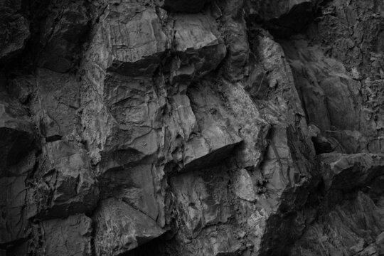Black white rock texture. Rough mountain surface. Close-up. Volumetric stone background with space for design. Dark gray grunge backdrop.