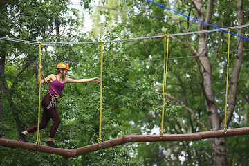 Naklejka na ściany i meble extreme vacation, girl in a yellow helmet rope park active holidays in the forest