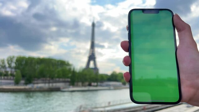 Phone with green Chromate screen on the background of the eiffel tower. in Paris using her cell phone in front of Eiffel Tower, seine bridge background, . High quality 4k footage