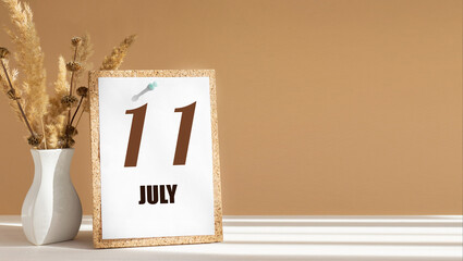 july 11. 11th day of month, calendar date.White vase with dead wood next to cork board with numbers. White-beige background with striped shadow. Concept of day of year, time planner, summer month