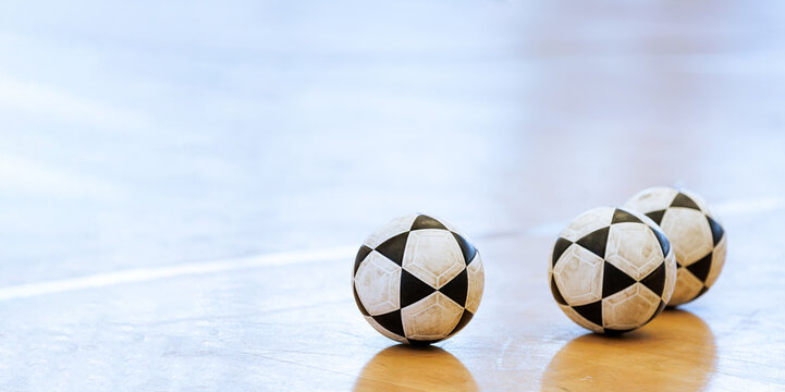 Three footballs on the gym floor background.