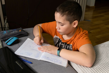 Naklejka premium Child using gadgets to study. Education and distance learning for kids. Preteen schoolboy doing her homework with digital tablet at home. Homeschooling during quarantine. Stay at home entertainment.