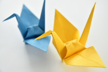 Blue and yellow origami paper cranes on white background.