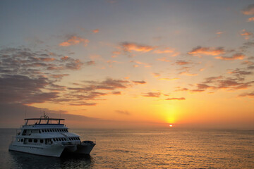 Obraz premium Typical tourist boat anchored near Santa Fe Island at sunrise, Galapagos National Park, Ecuador.