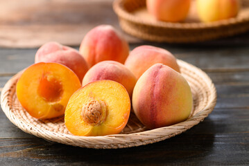 Naklejka na ściany i meble Peach fruit in basket on wooden background
