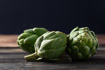 Obraz premium Green artichoke on wooden background, Edible flower bud