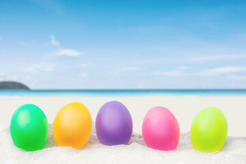colorful eggs on white sand beach over blue sea background.