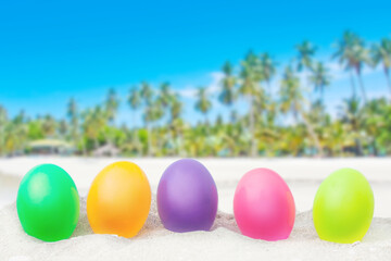 colorful eggs on white sand beach over blue sea background.