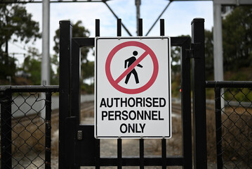 Authorised personnel only sign on a black metallic gate, with black fencing either site - obrazy, fototapety, plakaty