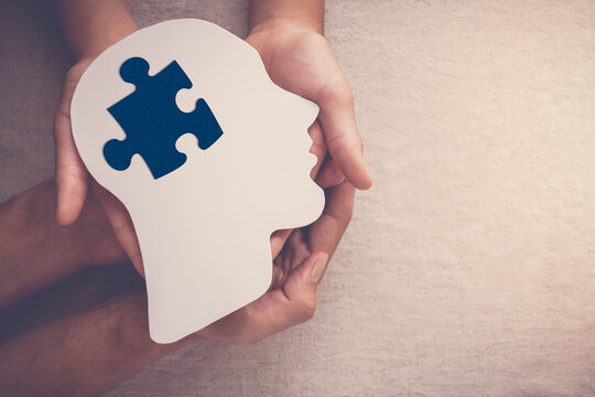hands holding puzzle piece missin in brain paper cutout, autism, dementia, mental health concept