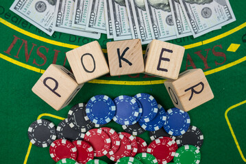 Word pokerr on wooden dice. Poker chips and dollars on a green poker table. View from above.