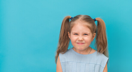 Angry furious child grimacing make face over blue background. - obrazy, fototapety, plakaty
