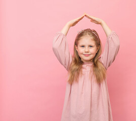 Portrait of little smiling girl making house or roof of hands isolated on pink colored background.  Safety or insurance concept.