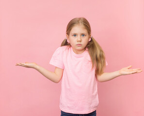 Pretty clueless girl shrugging shoulders gesturing I don't know. Pussled child on pink background portrait.