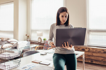 Obraz na płótnie Canvas Woman sits on desktop with laptop in hand