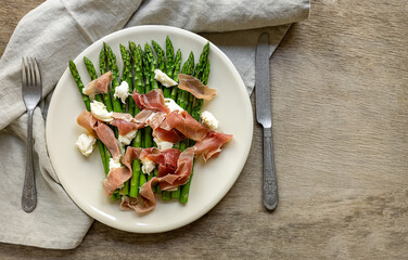 Green asparagus with mozzarella cheese and prosciutto ham. Seasonal delicious food. keto dietary...