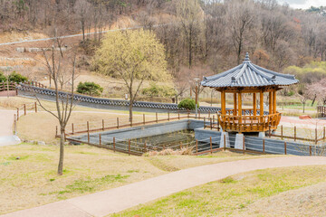 Oriental gazebo beside man made pond in mountainside public park.