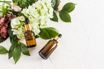Fashionable cosmetic product in glass bottles on a white background with fresh flowers. oil or serum for self-care. organic remedy.