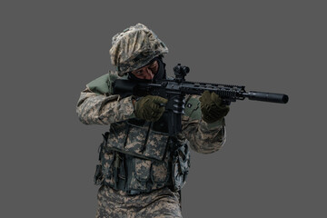 Portrait of professional military man dressed in camouflage helmet and uniform aiming rifle.