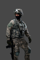 Shot of military man dressed in modern camouflage clothes holding rifle.