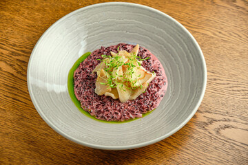 Risotto on a white restaurant plate with cuttlefish ink