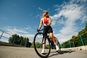 Happy summer low angle portrait a woman cyclist with curly hair in a helmet
