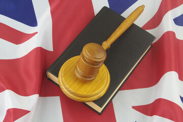 Book and wooden judge gavel on British flag. Concept of laws and court in United Kingdom.