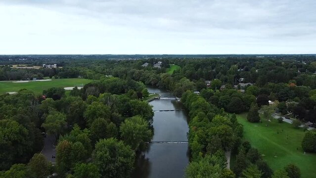 High HD Drone Flight over Speed River in Guelph, Ontario, Canada through Inner City Park with Patrons Enjoying the Spring Day