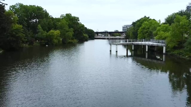 Low Drone Flying Through River Canal by White Docks and Water Birds with Train Tracks and Inner City Apartment Condos in Distance