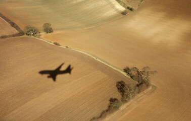 shadow of plane coming to landing at London Luton Airport, taken from the plane, beautiful fields like carpets down there 
