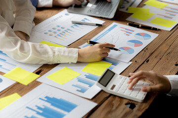 A desk in a company conference room has a group of business people attending and with supporting documents laid out, brainstorming sessions to fix and plan the company's growth. Business meeting idea.