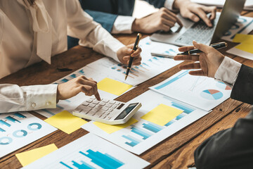 A desk in a company conference room has a group of business people attending and with supporting...