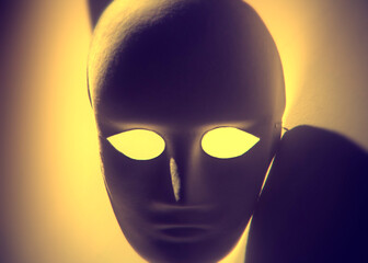 A blank anonymous mask, looking at the viewer, with an ominous shadow effect. Yellow coloring.
